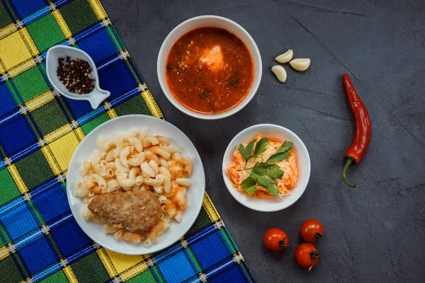 Комплект включает мясную котлету с макаронами, томатный суп, морковный салат с сыром — стоковое фото
