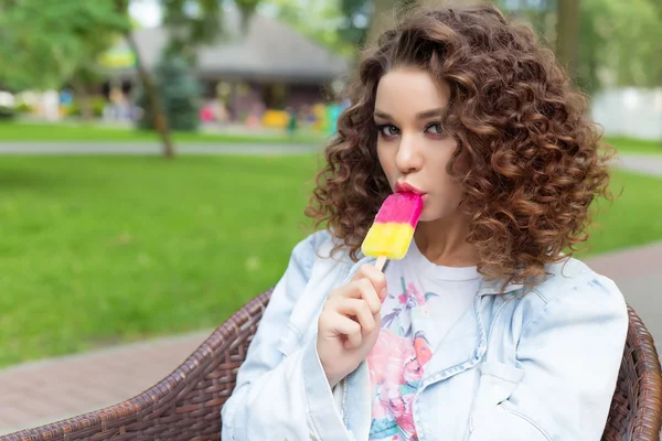 beautiful sexy cheerful girl with curly hair with full lips bright color eating ice cream in the park in a summer cafe