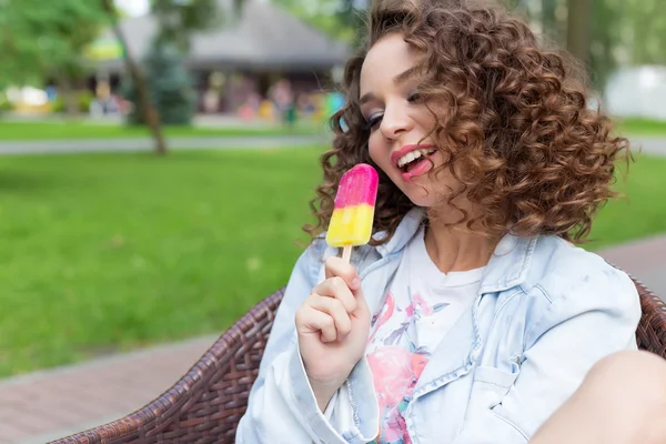 Schöne sexy fröhliches Mädchen mit lockigem Haar mit vollen Lippen helle Farbe Eis essen im Park in einem Sommercafé — Stockfoto