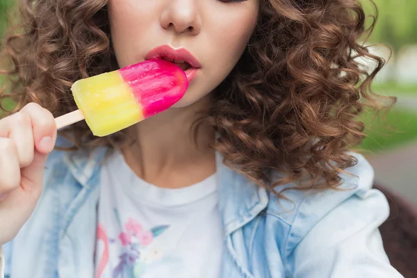 Beautiful girl with curly with a naked sexy lips eating color ice cream in a cafe in the park a bright summer day — Stock Photo, Image