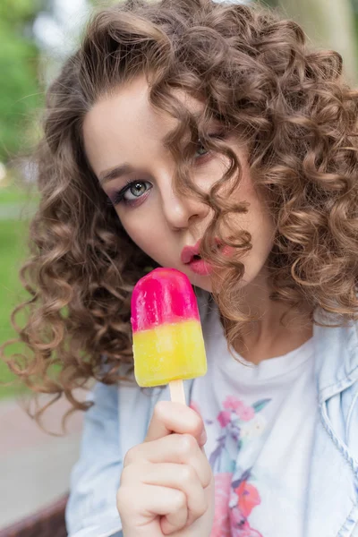 Beautiful girl with curly with a naked sexy lips eating color ice cream in a cafe in the park a bright summer day — Stock Photo, Image