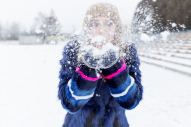 Mavi paltolu karda oynarken güzel parlak neşeli kız