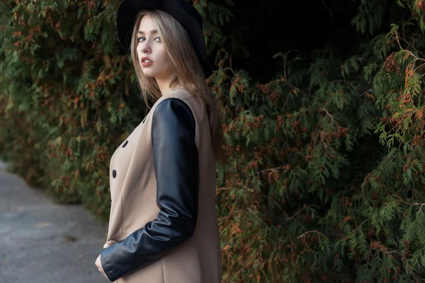 Lonely sad pretty cute blond girl with blue eyes and full lips in black hat and coat walking in autumn forest — Stock Photo, Image