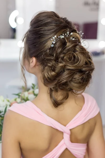 Hermoso peinado de noche elegante en el pelo oscuro hermosa chica con un ornamento de piedras en su cabello, peinado para la boda — Foto de Stock