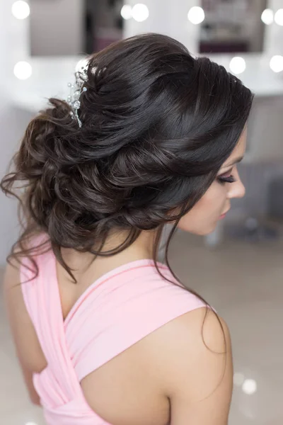 Belo penteado elegante noite no cabelo escuro menina bonita com um ornamento de pedras em seu cabelo, penteado para o casamento Fotografias De Stock Royalty-Free