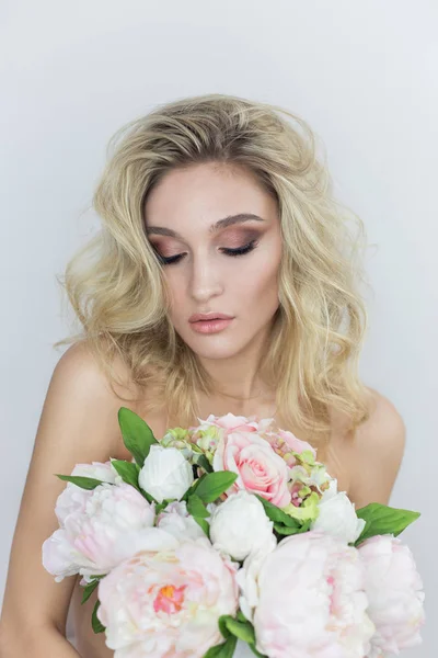 Ritratto di una bella giovane donna sexy con trucco luminoso con spalle nude che tiene un grande bouquet in mano su uno sfondo bianco — Foto Stock