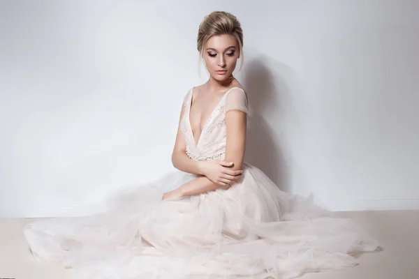 Bela noiva delicada menina sexy no vestido de noiva skazachno rosa macio com um corte no peito e nas costas com maquiagem e penteado da noite no estúdio em um fundo branco — Fotografia de Stock