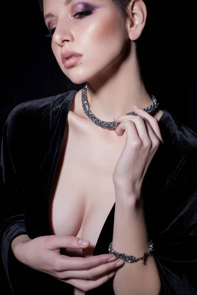 Beautiful sexy sensual young girl with short hair with bright makeup in the nude, beautiful evening jewelry earrings, necklaces, bracelets Fashion shot on a black background in the studio — Stock Photo, Image