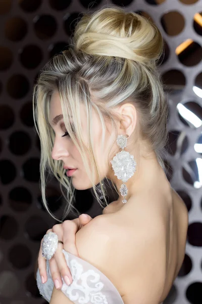 Elegante bella sposa ragazza con una bella sposa capelli festivi in un abito da sposa con ornamenti sulla testa, grandi orecchini di cristallo e anello — Foto Stock