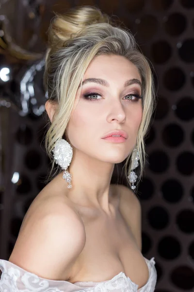 Retrato suave de una hermosa novia feliz lindo con un hermoso peinado festivo maquillaje brillante en un vestido de novia con pendientes y un anillo con un adorno en su cabello —  Fotos de Stock