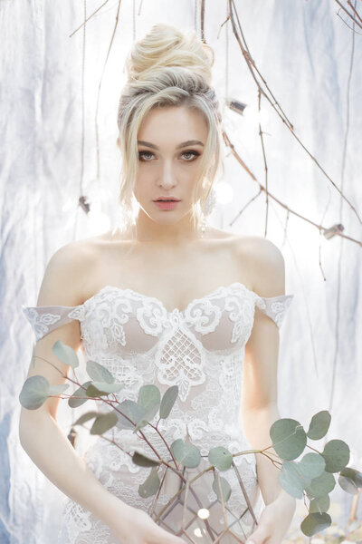 gentle portrait of a beautiful cute happy bride with a beautiful hairdo festive bright make-up in a wedding dress with earrings and a ring with an ornament in her hair
