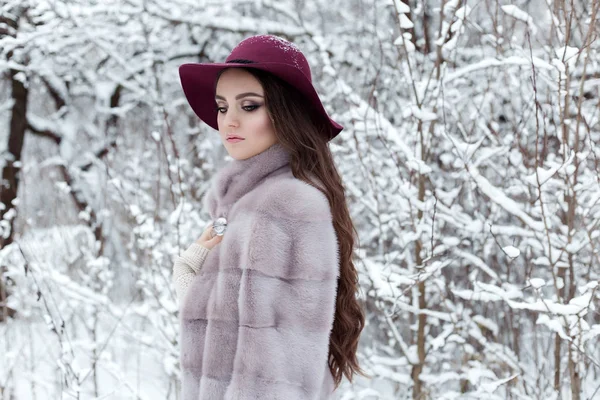 Mooi leuk elegant meisje in een bontjas en hoed wandelen in het bos heldere frosty winterochtend — Stockfoto