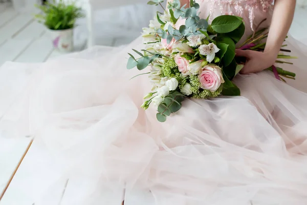 Hermoso ramo elegante de rosas y vegetación en las manos suaves de la hermosa novia chica en un vestido rosa el aire — Foto de Stock