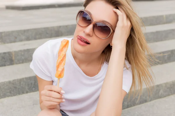 Schöne junge sexy Mädchen mit Sonnenbrille Eis essen auf der Leiter und lecken pralle Lippen einen hellen sonnigen heißen Tag — Stockfoto