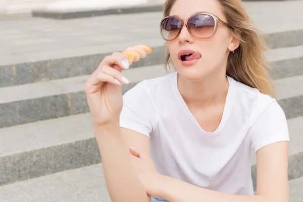 Piękna młoda seksowna dziewczyna w okulary jedzenia lodów na drabinie i lizanie plump usta w jasny, słoneczny dzień gorący — Zdjęcie stockowe