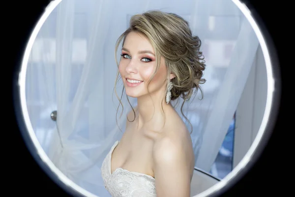 Sanftes Porträt einer schönen netten glücklichen Braut mit einer schönen Frisur festlich helles Make-up in einem Hochzeitskleid mit Ohrringen und einem Ring mit einem Ornament im Haar — Stockfoto