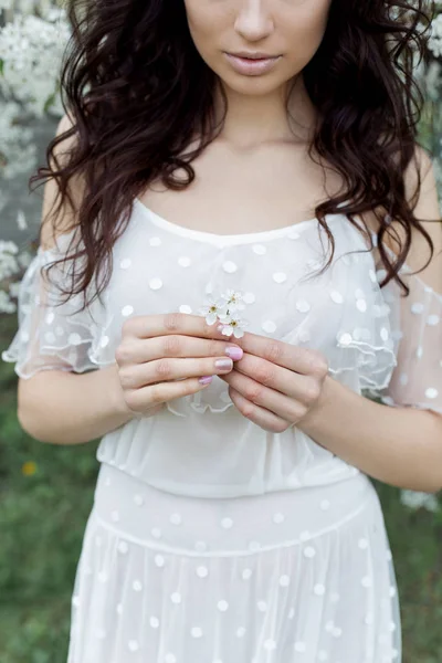 Beautiful sexy girl with a gentle make-up in a long light dress among the flowering trees walks in the spring garden on a warm sunny day — Stock Photo, Image
