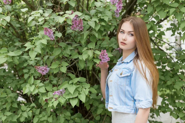 Красивая молодая девушка с рыжими волосами в саду с сиренью — стоковое фото
