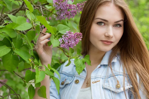 Beautiful young girl with red hair in the garden with lilac — Stock Photo, Image