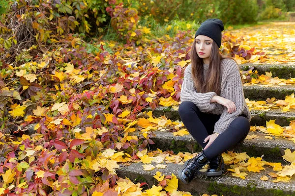Bella ragazza in autunno fogliame passeggiate per le strade della città in un pomeriggio di sole in un cappotto e una giacca calda — Foto Stock