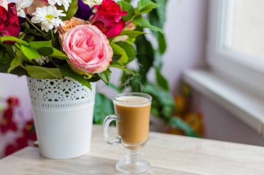 sıcak kahve süt ile pencerenin duruyor ve parlak renkli buket çiçek