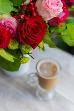 sıcak kahve süt ile pencerenin duruyor ve parlak renkli buket çiçek