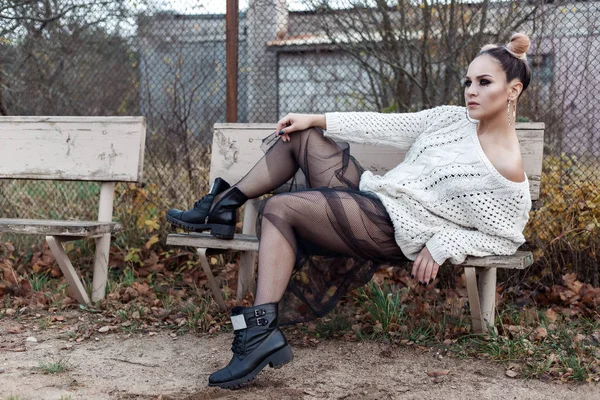 Hermoso tiro de moda de una chica en un suéter ancho blanco en zapatos y pantimedias en una red, maquillaje brillante y peinado —  Fotos de Stock