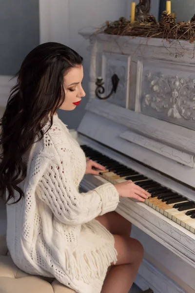 Belle fille mignonne en veste chaude blanche à la maison en jouant sur vieux piano — Photo