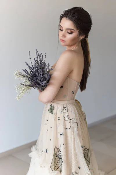 Hermosa chica morena sexy en vestido elegante con tren largo con flores de lavanda — Foto de Stock