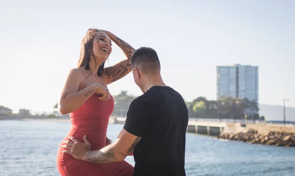 Joven pareja disfrutando de su amor en una puesta de sol frante al mar