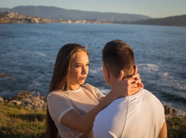 Joven pareja disfrutando de su amor en una puesta de sol frante al mar