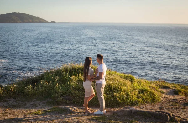 Joven pareja disfrutando de su amor en una puesta de sol frante al mar