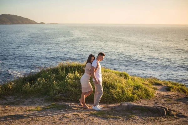 Joven pareja disfrutando de su amor en una puesta de sol frante al mar