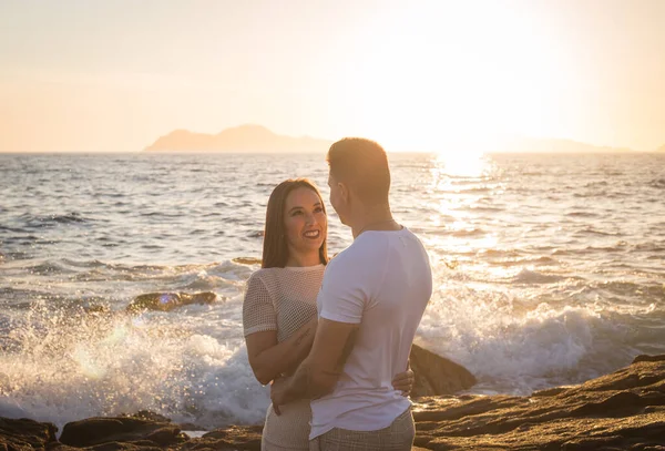 Joven pareja disfrutando de su amor en una puesta de sol frante al mar