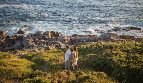 Joven pareja disfrutan de su amor frante una puesta sol en el mar