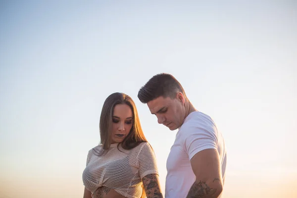 Joven pareja disfrutan de su amor frante una puesta sol en el mar