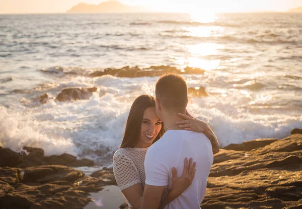 Joven pareja disfrutan de su amor frante una puesta sol en el mar