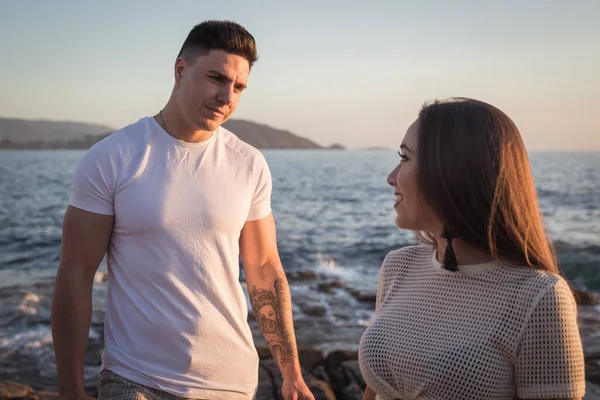 Joven pareja disfrutan de su amor frante una puesta sol en el mar