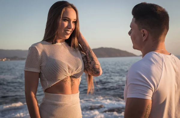 Joven pareja disfrutan de su amor frante una puesta sol en el mar