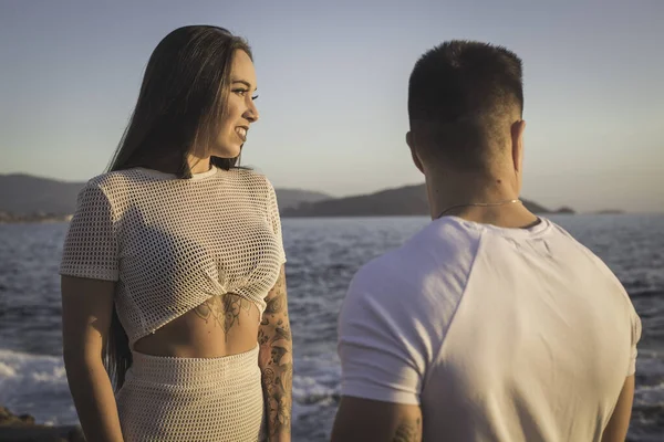 Joven pareja disfrutan de su amor frante una puesta sol en el mar