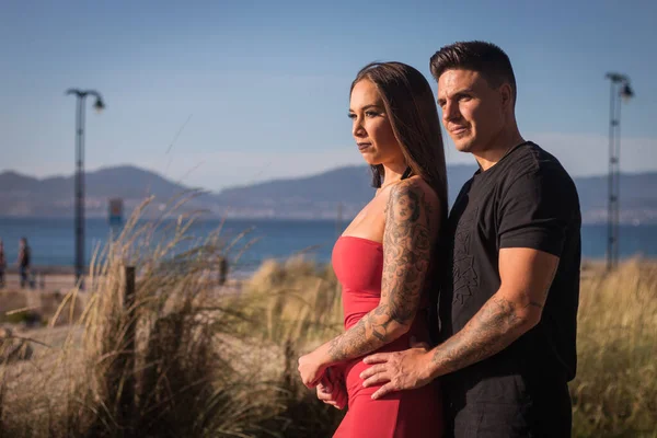 Joven pareja disfrutando de un paseo en una puesta de sol frante al mar