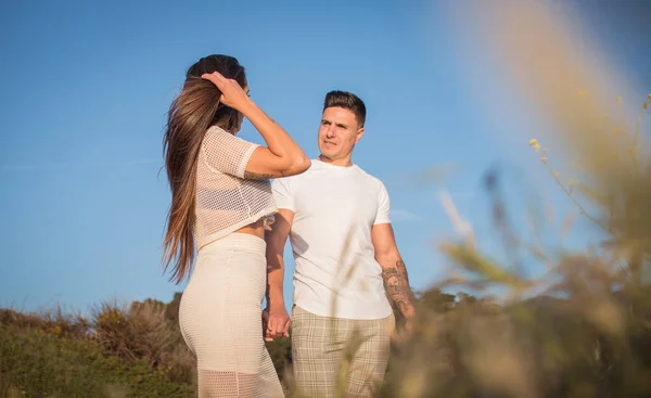Joven pareja disfrutando de un paseo en una puesta de sol frante al mar