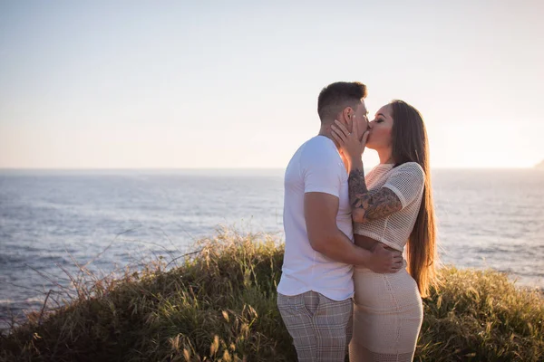 Joven pareja disfrutando de un paseo en una puesta de sol frante al mar