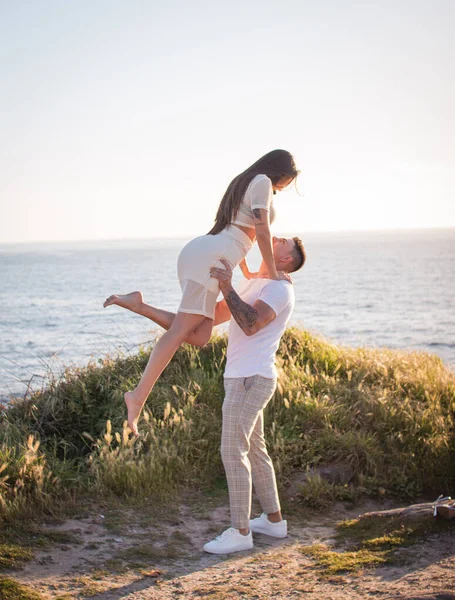 Joven pareja disfrutando de un paseo en una puesta de sol frante al mar