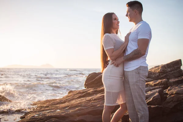Joven pareja disfrutando de un paseo en una puesta de sol frante al mar