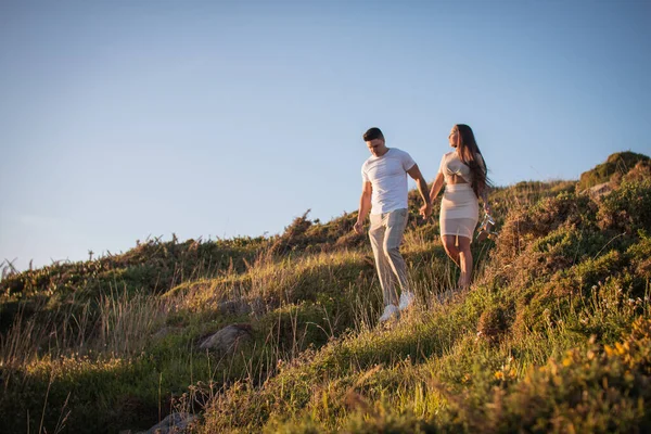 Joven pareja disfrutando de un paseo en una puesta de sol frante al mar