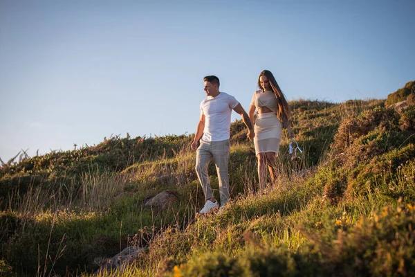 Joven pareja disfrutando de un paseo en una puesta de sol frante al mar
