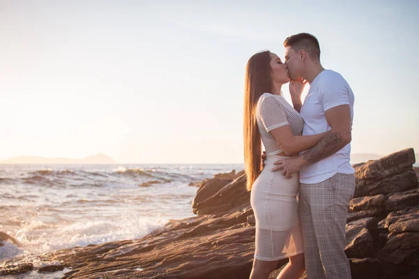 Joven pareja disfrutando de un paseo en una puesta de sol frante al mar