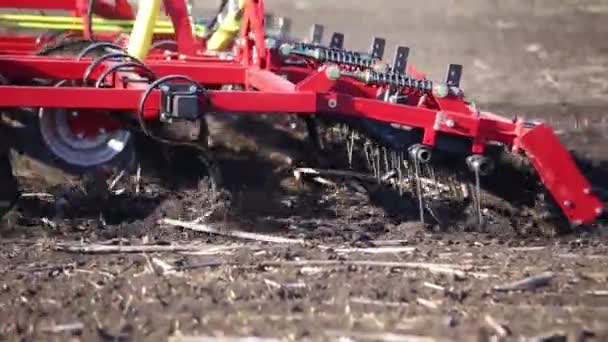 Red cultivator plows the ground on the field — Stock Video