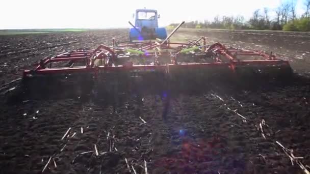 Cultivador vermelho arado o chão no campo — Vídeo de Stock